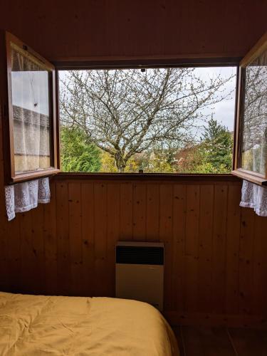 1 dormitorio con cama y ventana grande en Au petit chalet d'Illiers Combray en Illiers