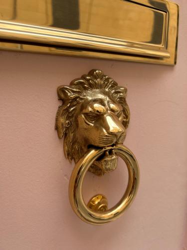 einen goldenen Türgriff mit einem Löwenkopf an der Wand in der Unterkunft MCC Argotti House in Floriana