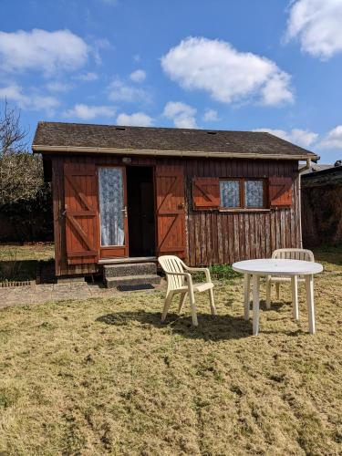 Cabaña pequeña con mesa y sillas frente a ella en Au petit chalet d'Illiers Combray en Illiers