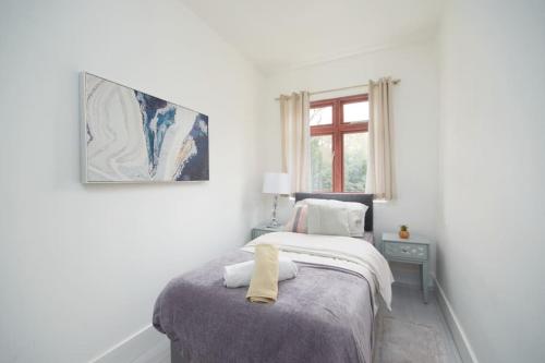 a white bedroom with a bed with a yellow towel on it at Large London home with Free parking in Winchmore Hill