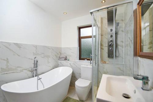 a bathroom with a tub and a toilet and a sink at Large London home with Free parking in Winchmore Hill