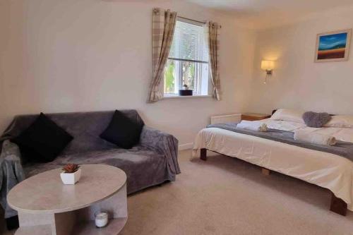 a living room with a couch and a bed and a table at 3 Bedroom Bungalow with great Sea Views, Private Hot Tub & Gardens in Paignton