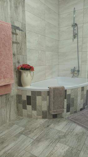 a bathroom with a bath tub with a vase of flowers at Lushof Guesthouse in eMalahleni