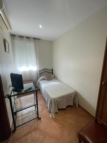 a bedroom with a bed and a table with a laptop at HOSTAL CHIQUININO II in Higuera la Real