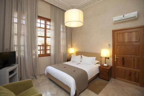 a bedroom with a large bed and a television at Domaine Rosaroum in Marrakech