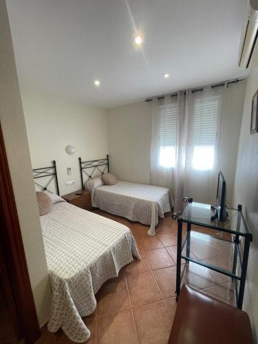 Habitación con 2 camas y TV. en HOSTAL CHIQUININO II, en Higuera la Real