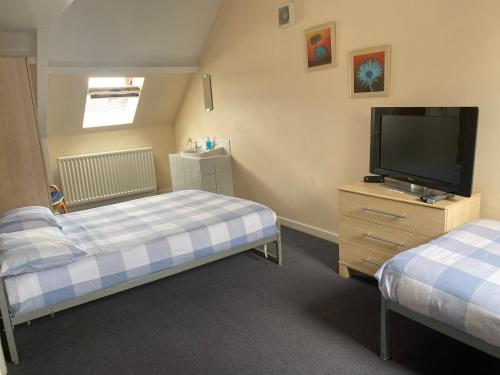a bedroom with two beds and a flat screen tv at Athol House in South Shields