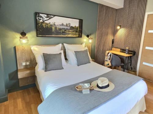 a hotel room with a bed with a hat on it at Logis Hôtel du Cygne in Bracieux