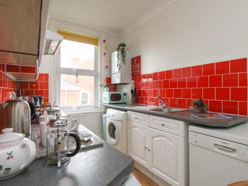 a kitchen with red tiles on the wall at Victoria Court in Weymouth