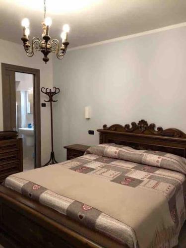 - une chambre avec un grand lit et un lustre dans l'établissement APPARTAMENTO POGGIGRILLi, à Pievepelago
