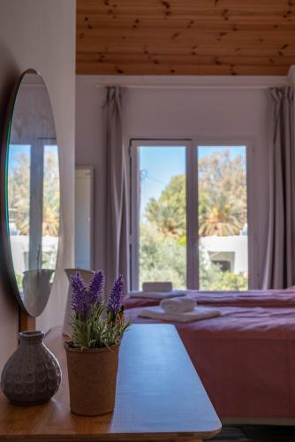 a bedroom with a bed with a mirror and purple flowers at Villa Meltemi in Daratso