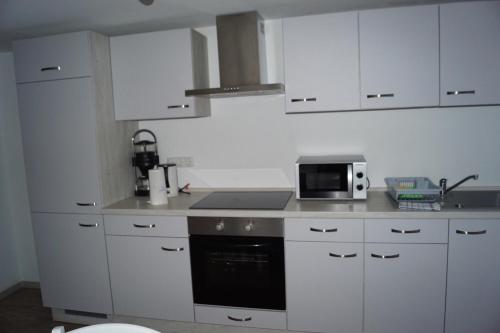 a kitchen with white cabinets and a microwave at Landhaus Eickhof in Niederhaverbeck