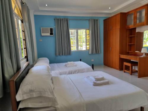 2 camas en una habitación con paredes y ventanas azules en Bretthouse Tourist Inn, en Lila
