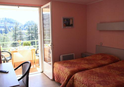 une chambre d'hôtel avec un lit et une porte coulissante en verre dans l'établissement Hotel Saint Jacques, à Vals-les-Bains