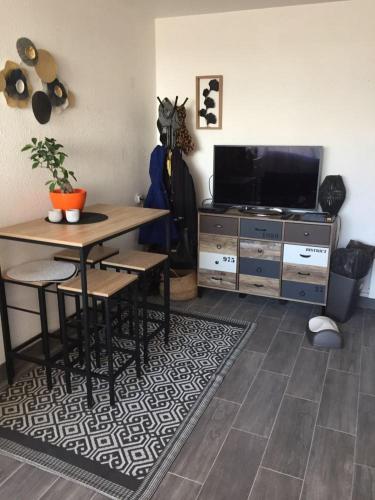 un salon avec une table et une télévision dans l'établissement Appartement T2 27m² meublé, vue mer à 50m de la plage, à Narbonne-Plage