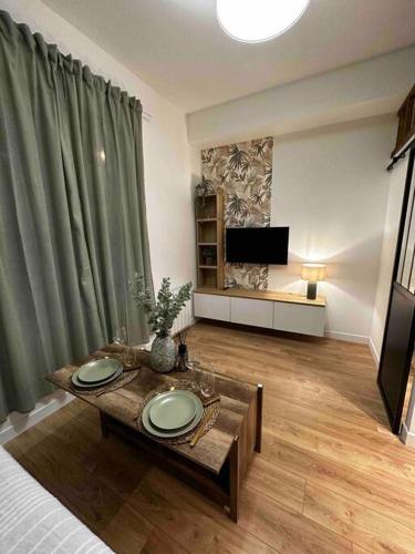 a living room with a table and a television at Le P’tit Antoine in Pont-lʼÉvêque