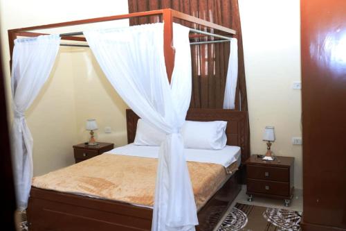 a bedroom with a canopy bed with white drapes at Happiness Guest House in Luxor