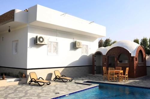 una casa con piscina al lado de una casa en Happiness Guest House, en Luxor