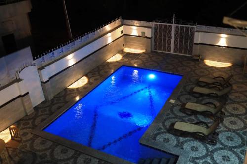 a swimming pool with blue lighting on a patio at night at Happiness Guest House in Luxor