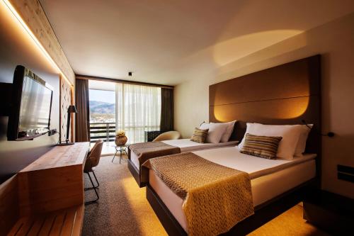 a hotel room with two beds and a television at Rikli Balance Hotel – Sava Hotels & Resorts in Bled