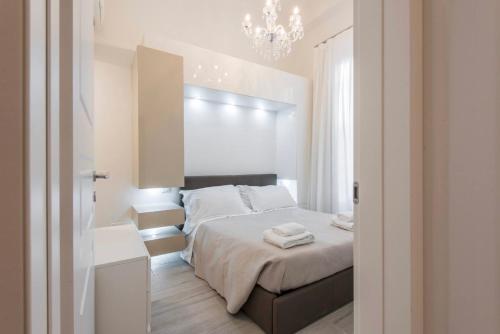 ein weißes Schlafzimmer mit einem Bett und einem Kronleuchter in der Unterkunft Modern Apartment in Florence in Florenz