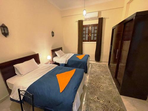 a bedroom with two beds with orange and blue sheets at Happiness Guest House in Luxor