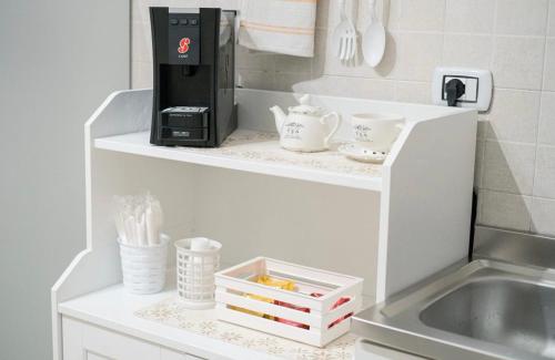 a coffee maker on a white shelf next to a sink at La casa di mammina in Bari