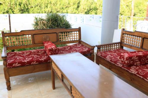 two benches with red cushions sitting on a balcony at Happiness Guest House in Luxor