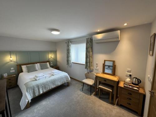 1 dormitorio con cama, escritorio y espejo en Royal Oak Guesthouse, en Islas Orcadas