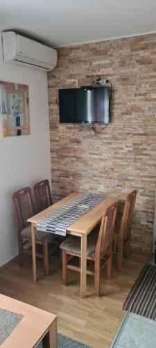 a wooden table with chairs and a television on a brick wall at Vila Dubrovnik in Vrnjačka Banja