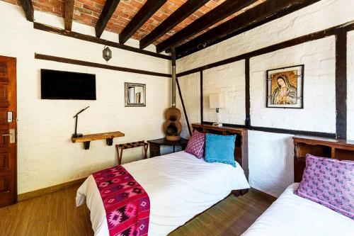 a bedroom with two beds and a tv in it at Increible Cuarto, Hostal Sobre el Centro de Valle in Valle de Bravo