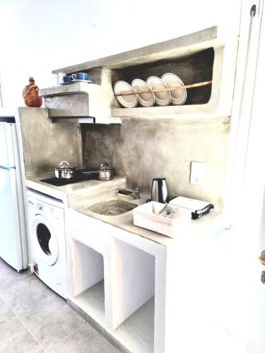 a kitchen with a sink and a washing machine at Joannes Vacation Rooms in Adamas