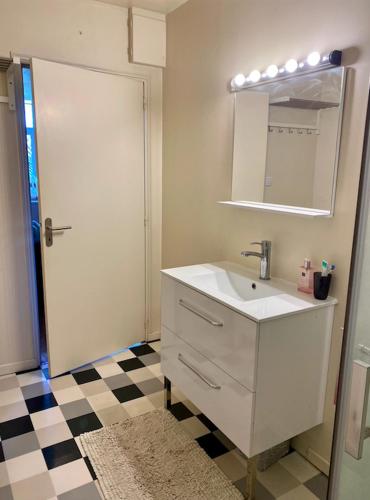 uma casa de banho com lavatório, espelho e piso em xadrez em La Ferme em Ascq