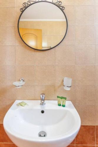 a bathroom with a white sink and a mirror at Eleanna Eco House, Solar-Powered Home with Sea Views in Agios Pavlos