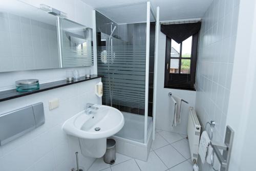 a white bathroom with a sink and a mirror at Pension Ari am See in Ostseebad Sellin