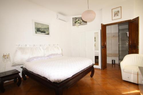 a white bedroom with a bed and a chair at B&B Palazzo Scaraggi Il Solito Posto in Bitonto