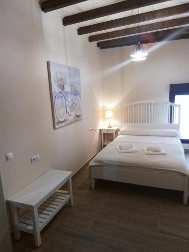 a bedroom with a white bed and a bench in it at Hostel & Rooms Casa Maia in Padrón