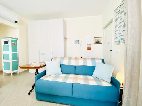 een blauwe bank in een woonkamer met een tafel bij Hostdomus - Bilocale da Patrizia in Finale Ligure
