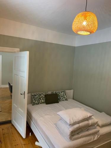 a bedroom with a bed with a chandelier at Tree Top Hill - The Old Station House - Båstad Holiday Apartments in Båstad