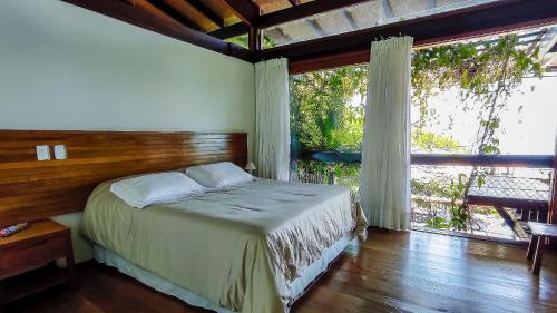 a bedroom with a bed and a large window at Casa com piscina e vista para o mar em Ilhabela in Ilhabela