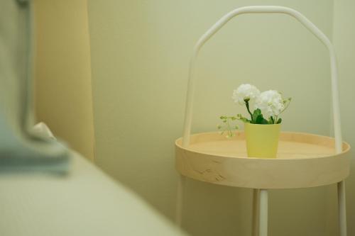 a small shelf with a vase with white flowers on it at In centro apartment in Palermo