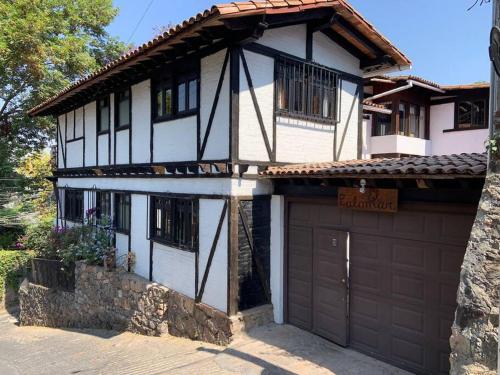 a white and black house with a garage at Cuarto Privado en Hostal Para 2 Personas Valle in Valle de Bravo