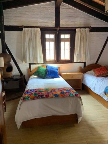 a bedroom with two beds and two windows at Cuarto Privado en Hostal Para 2 Personas Valle in Valle de Bravo