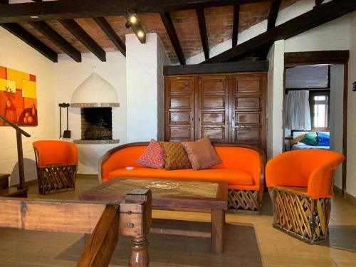 バジェ・デ・ブラボにあるCuarto Privado en Hostal Para 2 Personas Valleのリビングルーム(オレンジ色のソファ、暖炉付)