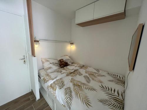 una piccola camera da letto con un letto con un orsacchiotto sopra di Appartement hyper centre de Cabourg avec balcon a Cabourg
