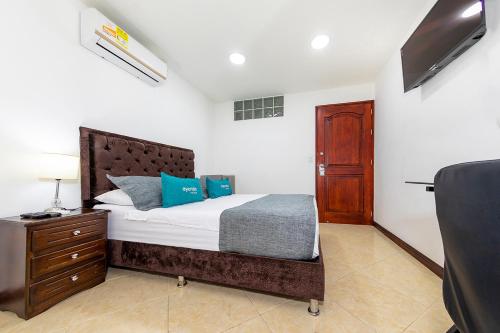 a bedroom with a bed and a dresser and a television at Hotel Ayenda Palo Alto in Medellín