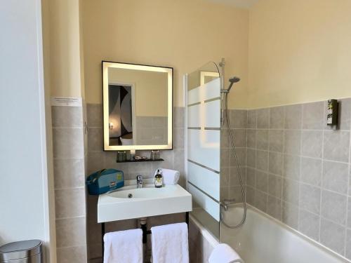 a bathroom with a sink and a mirror and a tub at Logis Hôtel du Cygne in Bracieux