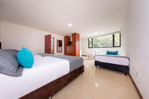 1 dormitorio con 2 camas y almohadas azules en Hotel Ayenda Palo Alto, en Medellín