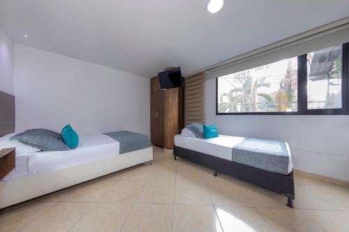 two beds in a room with a window at Hotel Ayenda Palo Alto in Medellín