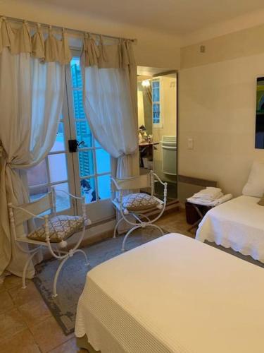 une chambre avec deux lits et deux chaises et une fenêtre dans l'établissement Charming Provencal Mas with amazing sea view and pool, à Saint-Tropez